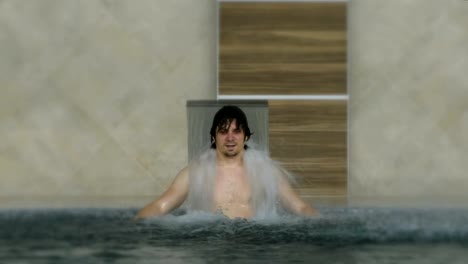 Young-man-enjoying-pool-spa-day-in-relaxing-vacation-resort.-Hydro-massage-for-neck-pain.Relaxing-under-water-jet,neck-and-spine-massage.