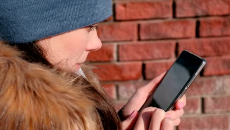 Woman-is-browsing-internet-pages-on-mobile-phone-in-winter-park.-Closeup-face.