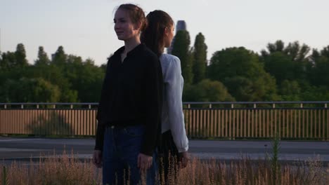 Two-Young-Women-Standing-Back-to-Back-in-a-Roundabout