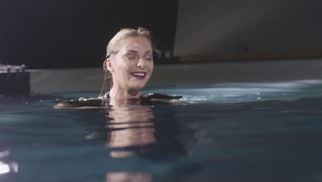 Smiling-woman-gesturing-and-posing-for-photo-or-video-in-swimming-pool