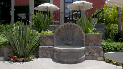 Outdoor-patio-and-garden-with-a-shell-fountain-and-tables-with-umbrellas