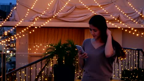 Mujer-asiática-haciendo-Selfie-con-un-el-teléfono-en-la-ciudad-de-noche-en-un-hotel-en-la-azotea.