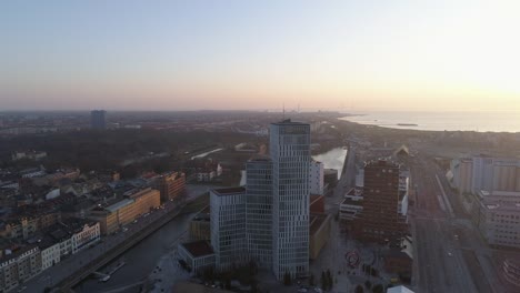 Aerial-view-of-Malmö-cityscape-skyline-at-sunset.-Drone-shot-flying-over-city-and-street-and-backwards-from-modern-skyscraper-building-downtown
