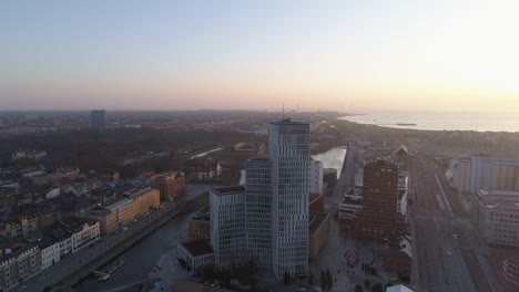 Luftaufnahme-von-Malmö-Stadtbild-Skyline-bei-Sonnenuntergang.-Drohne-Schuss-fliegen-über-Stadt-und-Straße-und-nach-hinten-von-modernen-Wolkenkratzers-Gebäude-Innenstadt