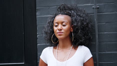 Fashionable-young-black-woman-leaning-against-a-wall-on-the-street,-close-up