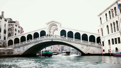 Barcos-pasando-bajo-increíble-puente-de-Rialto,-uno-de-los-símbolos-de-Venecia,-Italia-y-la-antigua-herencia-de-la-arquitectura-mundial.