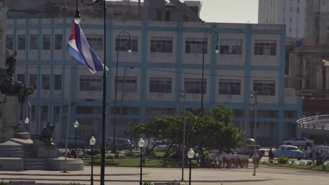 vida-cotidiana-en-la-Habana-Vieja,-los-niños-de-la-escuela-cubana-en-plaza-pública-con-la-bandera-cubana