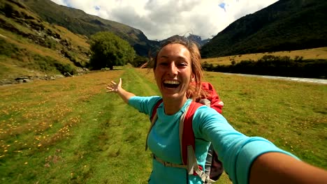 Cheerful-woman-takes-a-self-portrait-in-mountain-valley,
