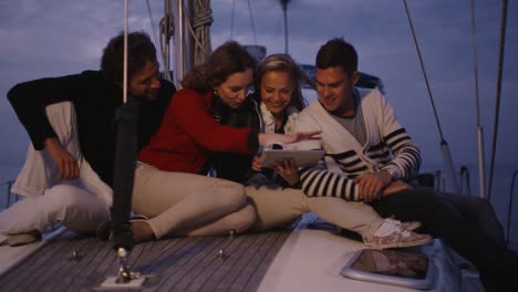 Gruppe-von-Menschen-nutzen-Tablet-auf-einer-Yacht-im-Meer-in-der-Nacht.