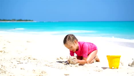 Entzückende-kleine-Mädchen-spielen-mit-Spielzeug-für-den-Strand-am-weißen-Sandstrand