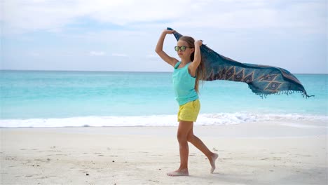 Niña-adorable-que-se-divierten-corriendo-con-pareo-en-la-playa-tropical