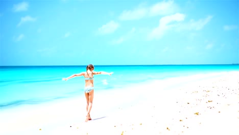 Active-little-girl-at-beach-having-a-lot-of-fun.-Sporty-kid-jumping-and-running-on-the-seashore.