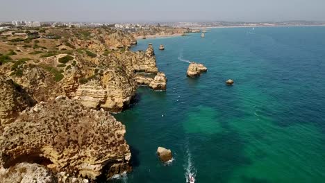 Aérea.-Captura-de-vídeo-abejón,-riffs-de-montañas,-sobre-la-bahía-de-Ponta-de-Piedade.-Lagos