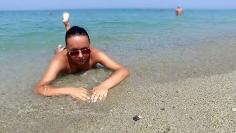 Sexy-girl-in-bikini-lying-on-a-sandy-beach-and-enjoy-wave-splashes