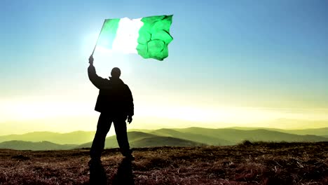 Ganador-de-hombre-exitoso-silueta-Nigeria-bandera-sobre-la-cima-de-la-montaña,-fondo-Cinemagraph-lazo