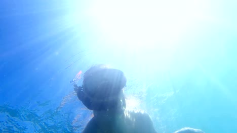 Men-doing-snorkeling-in-Caribbean-sea,-view-from-underwater-to-diver-and-sunrays,-uhd-shoot