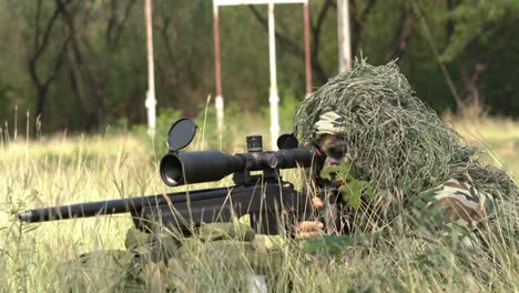 Francotirador-soldado-tendido-en-el-suelo-y-camuflaje-en-hierba.-Soldado-con-arma-pistola-y-waring-armadura-uniforme.-El-ejército-es-responsable-de-mantener-el-territorio.