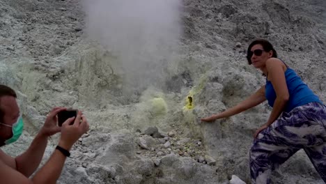 Un-hombre-es-tomar-fotografías-de-una-mujer-junto-a-una-fumarola-en-un-smartphone