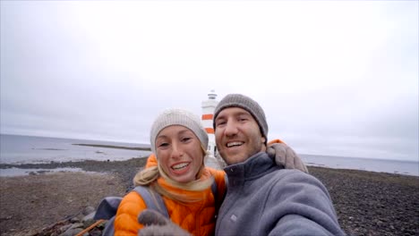 Travel-couple-taking-selfie-at-lighthouse,-girl-blowing-a-kiss