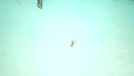 Drone-shot-aerial-view-of-young-man-lying-down-like-star-shape-on-idyllic-tropical-beach