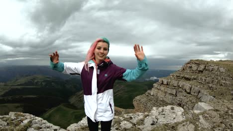 Girl-young-woman-dances-on-the-edge-of-a-cliff-of-a-plateau-having-fun-nature-mountains-flowers-beautiful-attractive-playing-cheerful-satisfied-joy-leisure-funny-laughing-smile-looking-camera-wonderful-landscape-summer-happy-weekend