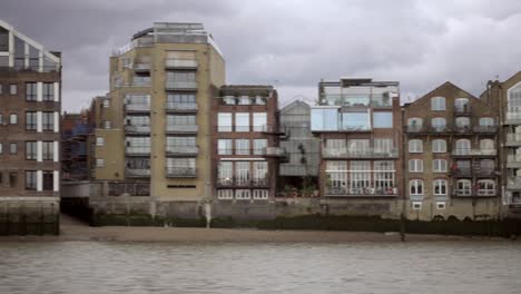 tracking-shot-passing-houses-and-structures-on-Thames-River-bank-in-London