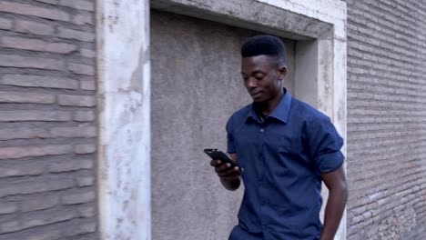 Attractive-black-african-man-walking-and-typing-on-his-smartphone