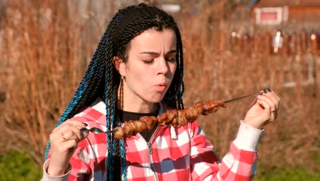 Woman-eating-meat-shashlik-barbecue-on-a-skewer-in-the-backyard-in-the-spring-on-a-Sunny-day.
