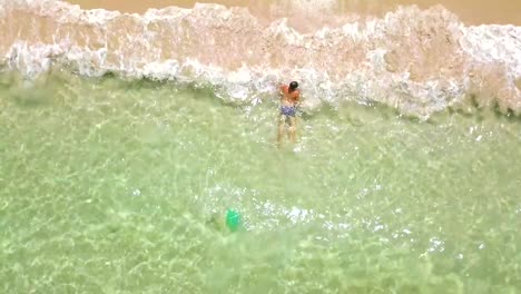 Man-swimming-in-crystal-clear-sea-water-drone-view-from-above.-Man-bathing-in-turquoise-sea-water-on-paradise-beach-aerial-view