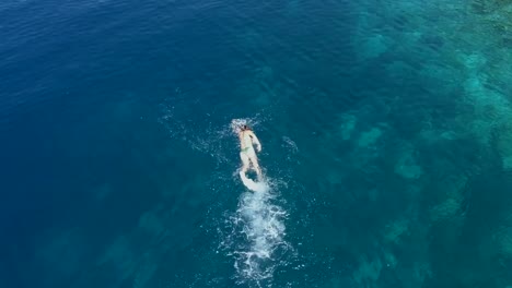 Luftaufnahmen-von-einem-Mädchen-schwimmen-im-blauen-Meer