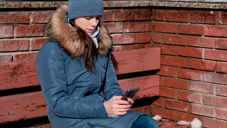 Frau-tippt-eine-Nachricht-auf-dem-Handy-im-Park-sitzen.