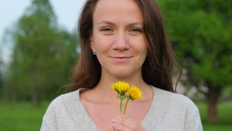 Woman-hold-in-hands-dandelion-flowers