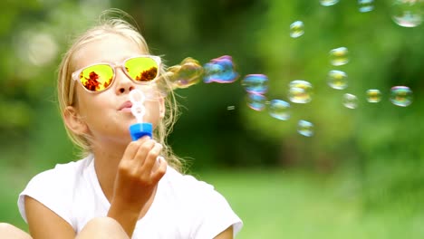 Little-girl-playing-with-soap-bubbles-outdoor.-Slow-motion.