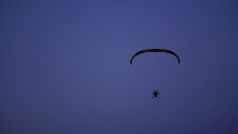 El-piloto-de-un-parapente-vuela-desde-la-cámara-poco-a-poco-alejándose-en-la-distancia-contra-el-cielo-azul