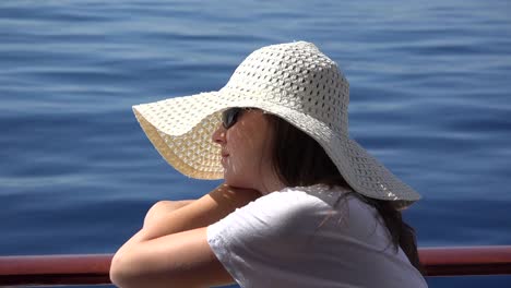 Hermosa-mujer-con-sombrero-blanco-tiene-un-crucero-en-mar-azul