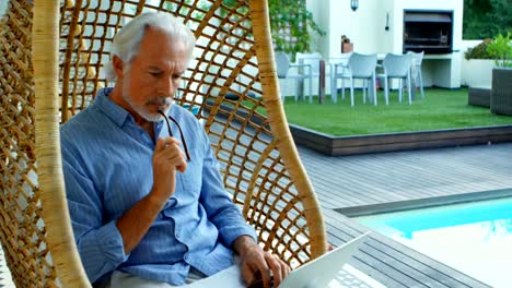 Senior-man-reading-a-book-while-sitting-on-hanging-chair-4k