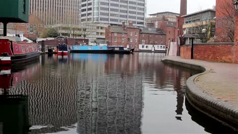 Schwenk-nach-oben-Spiegelung-im-Wasser,-High-Rise-Gebäude-und-traditionelle-Pub-am-Kanal