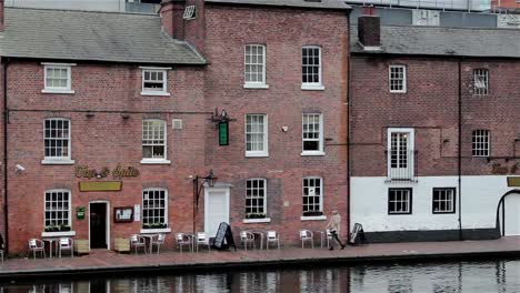 Menschen-am-traditionellen-Pub-am-Ufer-mit-Reflexionen-in-Canal