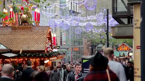 High-Street-luces-parpadeantes-de-navidad-compradores-en-el-concurrido-puesto-de-mercado-navideño-alemán