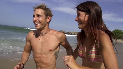 SLOW-MOTION:-Smiling-couple-running-along-the-sunny-beach