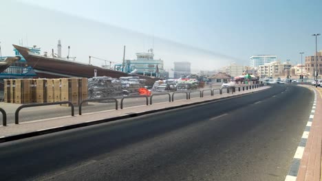 Boats-at-Port-Saeed-along-Deira's-shore-of-Dubai-Creek,-UAE.-Timelapse-view-from-road