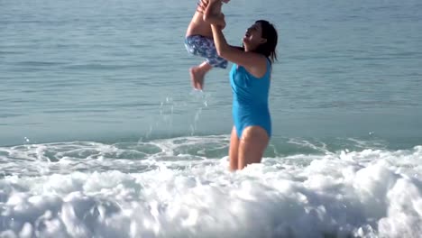 Mutter-und-junge-Jungen-spielen-im-seichten-Wasser-am-Strand,-Cape-Town