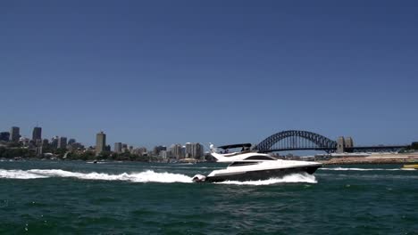 Speedboat-and-small-water-taxi-passing-by-in-front-of-the-harbour-bridge