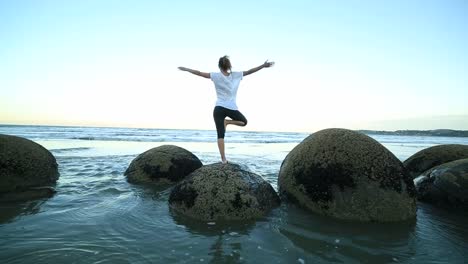 Female-exercises-yoga-on-a-boulder-by-the-sea