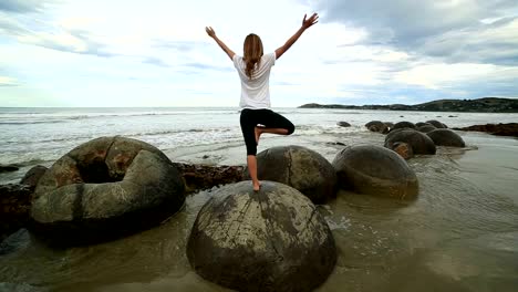 Female-exercises-yoga-on-a-boulder-by-the-sea