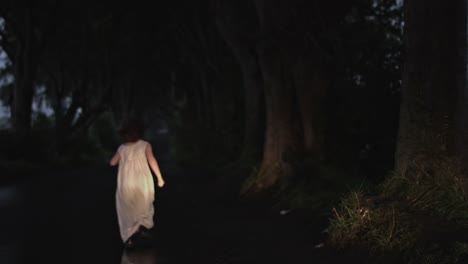 4k-Horror-Shot-of-Child-Running-Scared-in-Dark-Hedges,-N.-Ireland