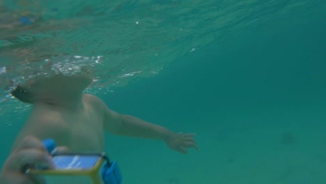 Niño-con-cámara-en-la-carcasa-impermeable-bañándose-en-el-mar