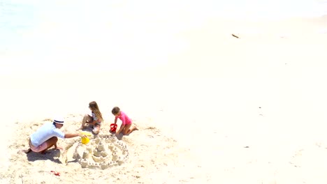 Blick-von-oben-auf-Vater-und-Töchter-machen-Sandburg-am-tropischen-Strand