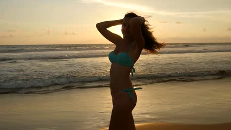 Chica-sexy-atractiva-con-el-pelo-largo,-posando-en-la-orilla-del-mar-al-amanecer.-Hermosa-mujer-joven-en-pie-bikini-cerca-del-mar-en-el-atardecer.-Mujer-en-la-playa-disfrutando-de-la-vida-durante-las-vacaciones.-Cierre-para-arriba