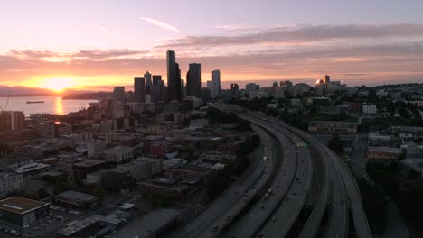 Aérea-del-Skyline-de-la-ciudad-de-Seattle-con-la-llamarada-de-la-lente-roja-de-puesta-de-sol-que-brilla-intensamente-del-helicóptero